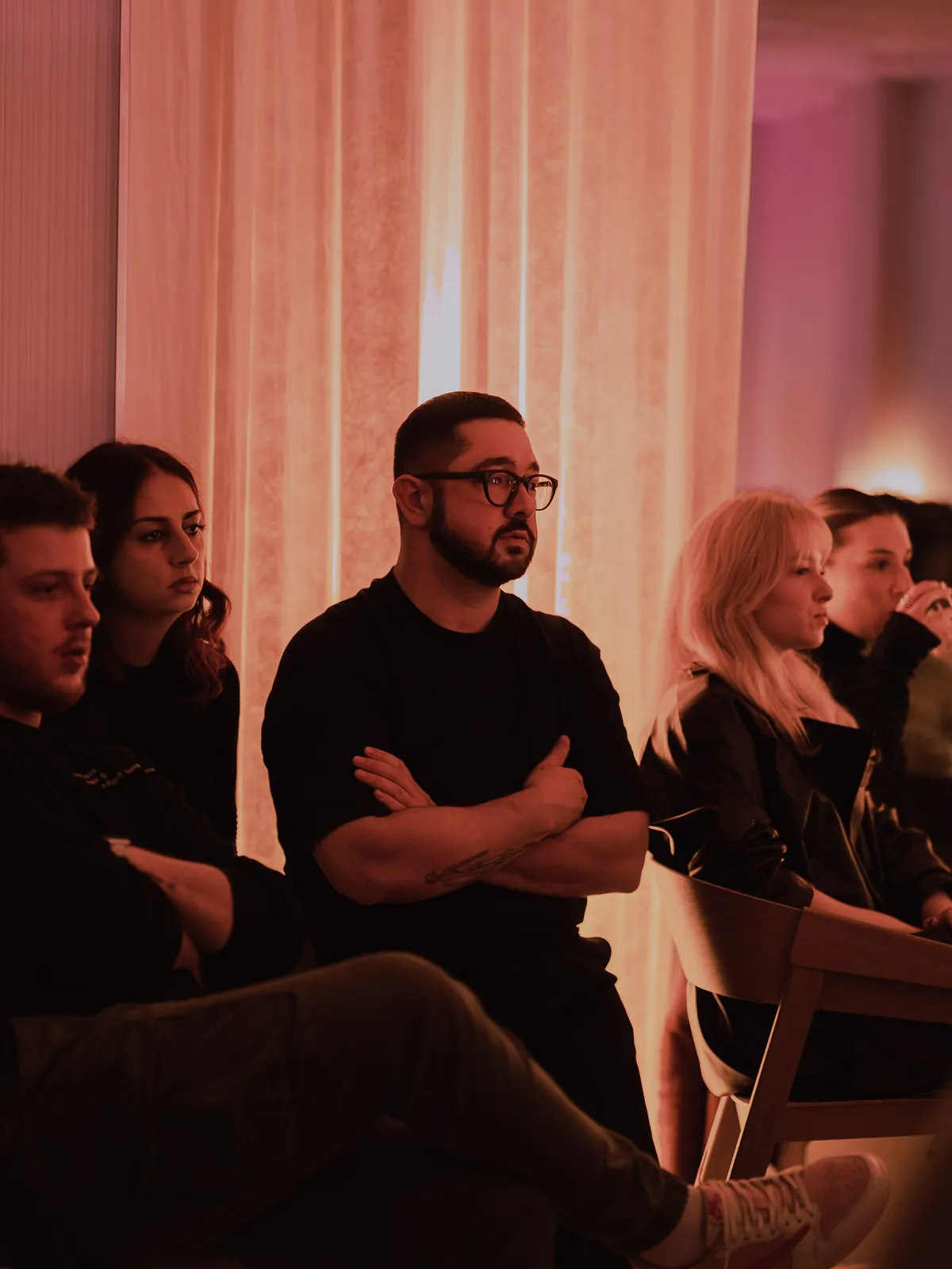 A guest in the audience, arms crossed, listening